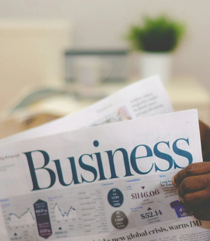 person wearing suit reading business newspaper